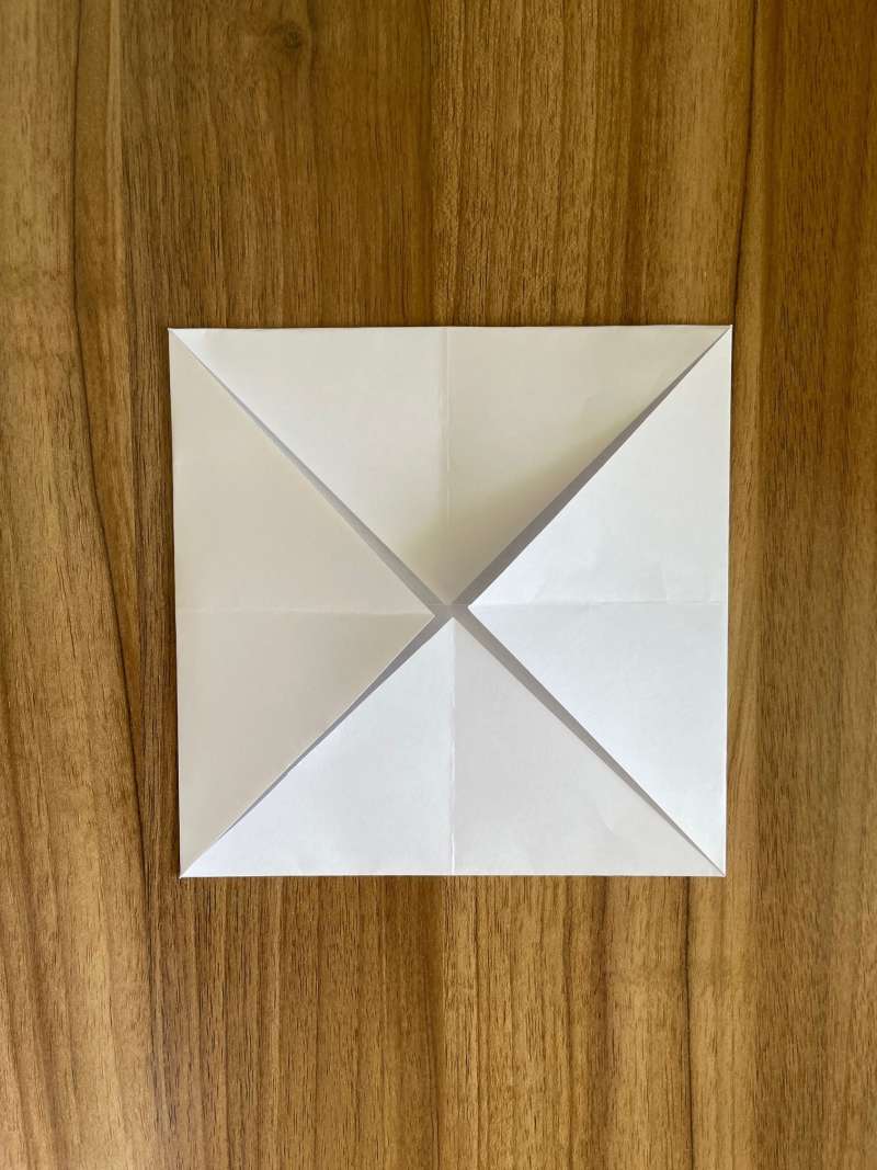 A piece of paper folded into 4 triangles that meet in the middle. A piece of paper folded into 4 triangles that meet in the middle.