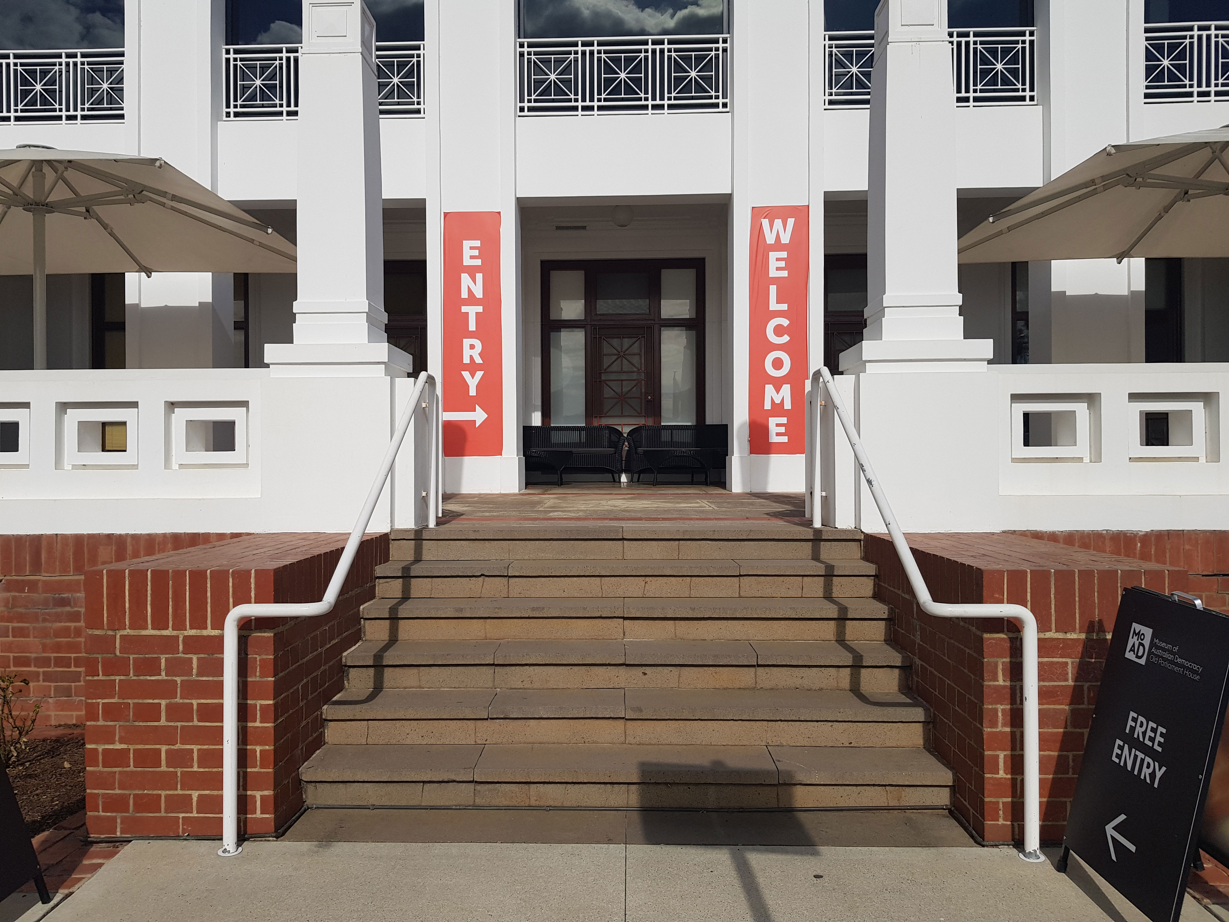 Stairs leading up to a white building with red banners and the signs 'Welcome'.