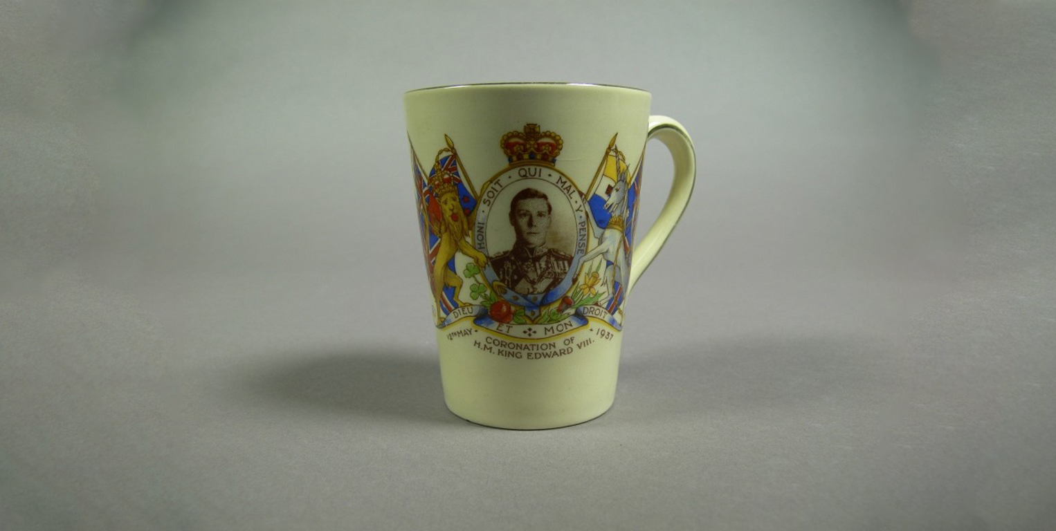 A ceramic mug featuring a portrait of Prince Edward, framed with the British coat of arms, with the words 'Coronation of H.M. King Edward VIII' and '12th May 1937'. A ceramic mug featuring a portrait of Prince Edward, framed with the British coat of arms, with the words 'Coronation of H.M. King Edward VIII' and '12th May 1937'.