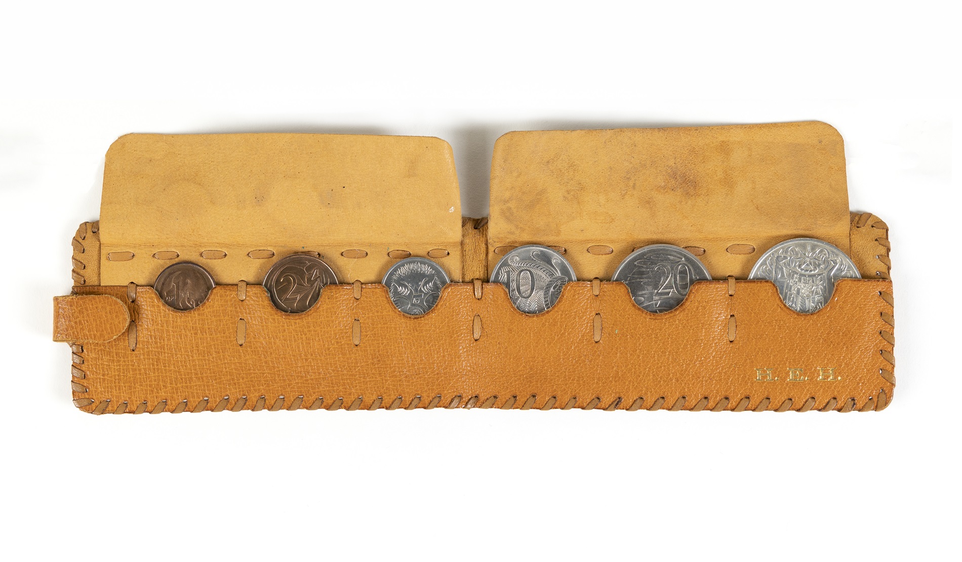 A leather pouch embossed with the letters H. E.H and holding a 1-cent, 2-cent, 5-cent, 10-cent, 20-cent and 50-cent coins A leather pouch embossed with the letters H. E.H and holding a 1-cent, 2-cent, 5-cent, 10-cent, 20-cent and 50-cent coins