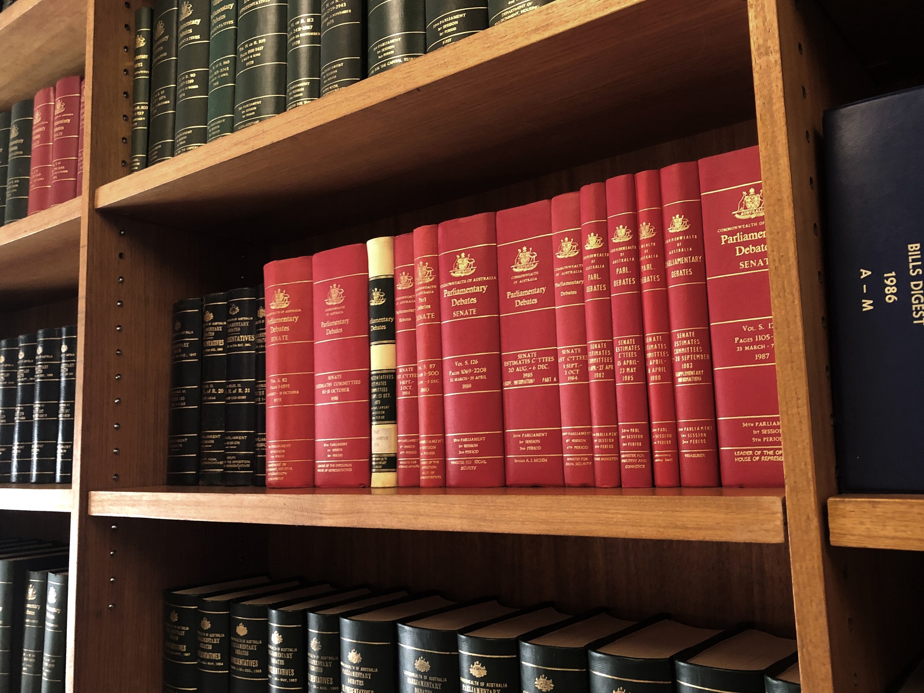 A row of red bound volumes on a shelf containing the proceedings of Senate Estimate committee hearings. A row of red bound volumes on a shelf containing the proceedings of Senate Estimate committee hearings.