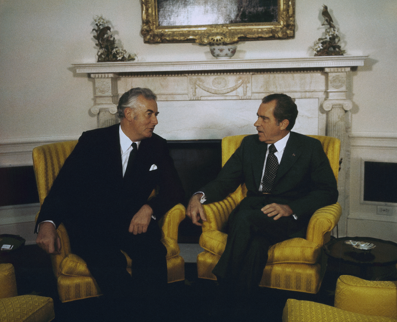 Richard Nixon and Gough Whitlam sit in yellow chairs in the Oval Office facing each other and talking. Richard Nixon and Gough Whitlam sit in yellow chairs in the Oval Office facing each other and talking.