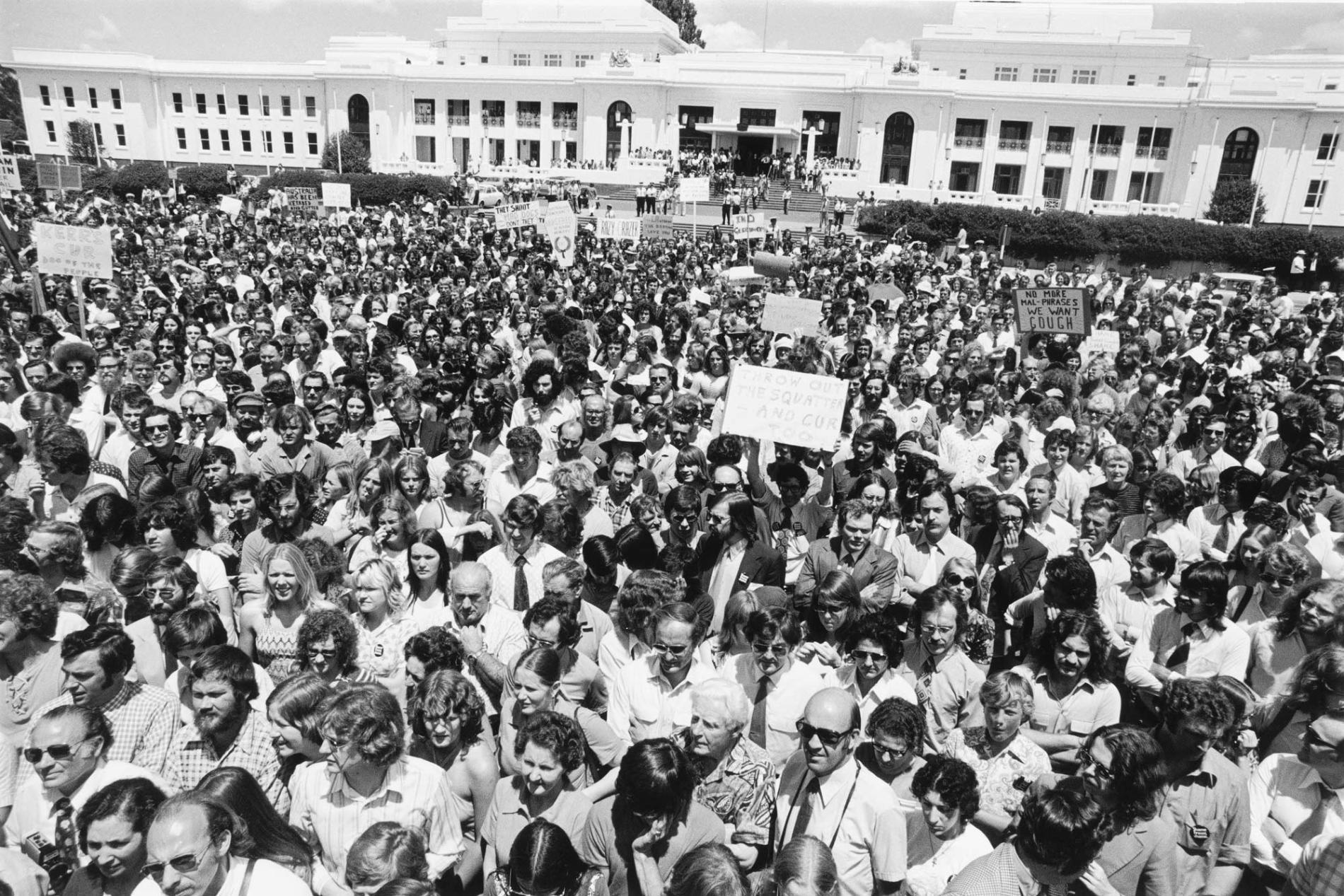 A large crowd of people gathered outside Parliament House, some holding placards. A large crowd of people gathered outside Parliament House, some holding placards.