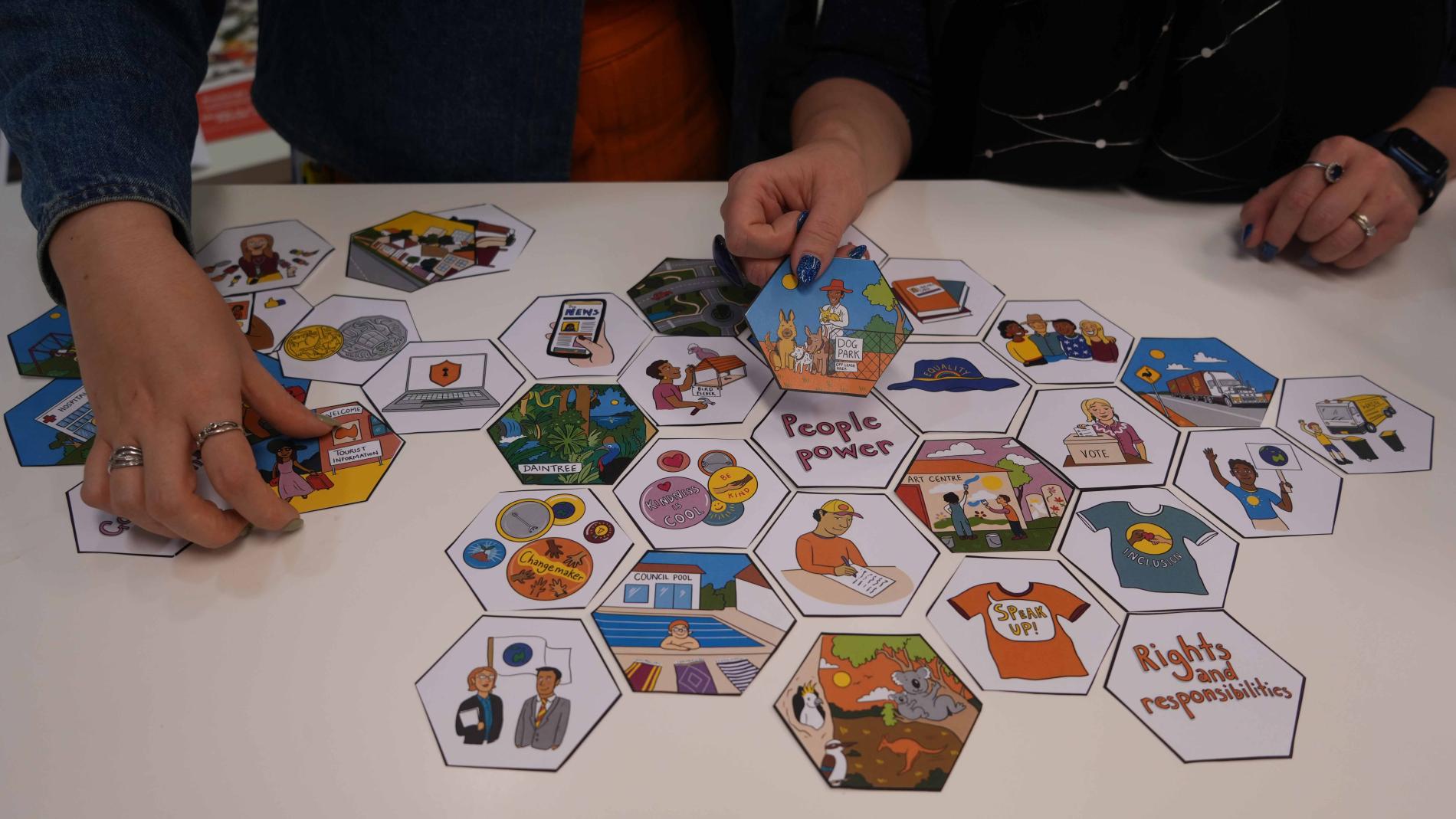 Hands move hexagon-shaped tiles featuring words and illustrations. 