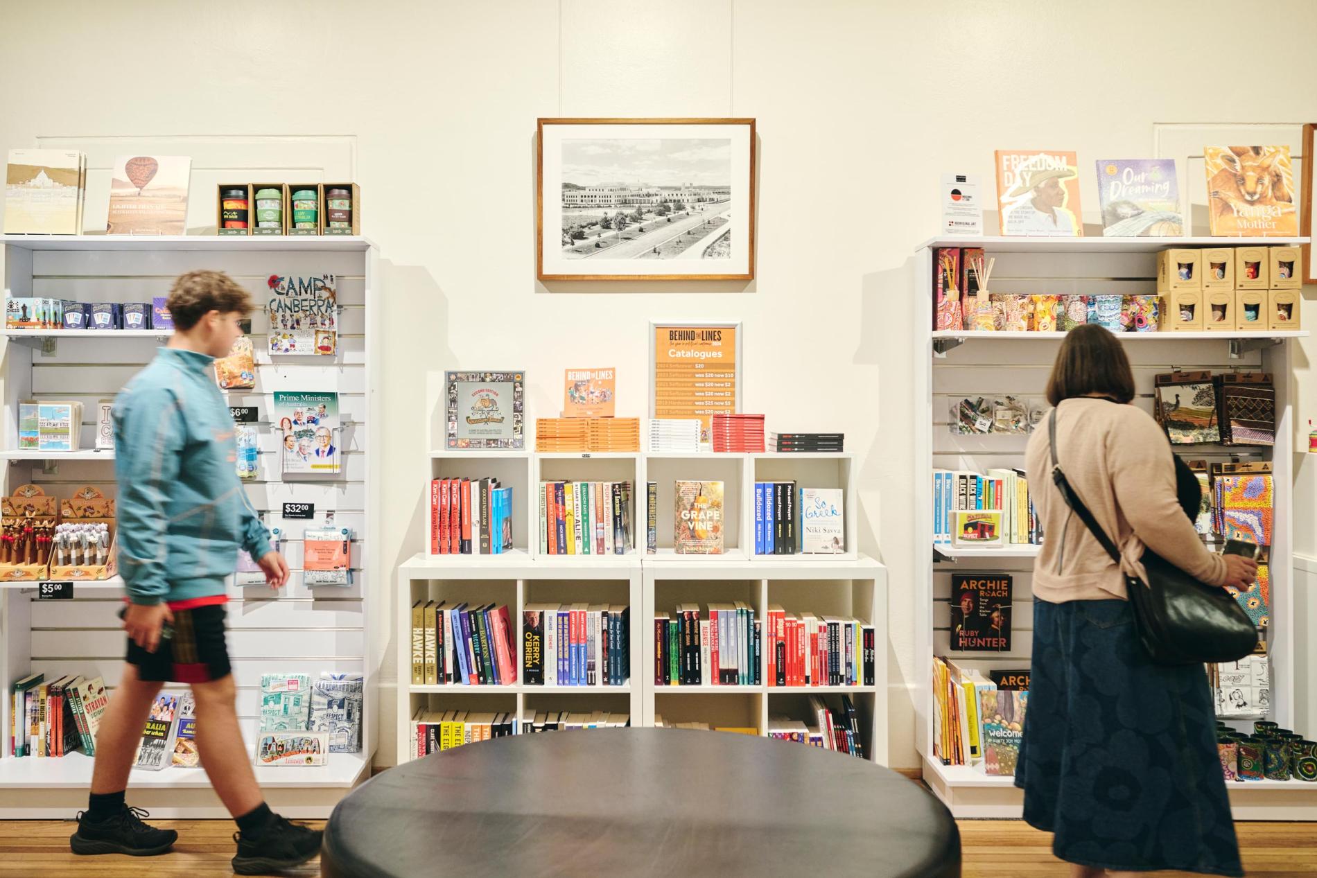 Two people browse books and other shop products on shelves. 
