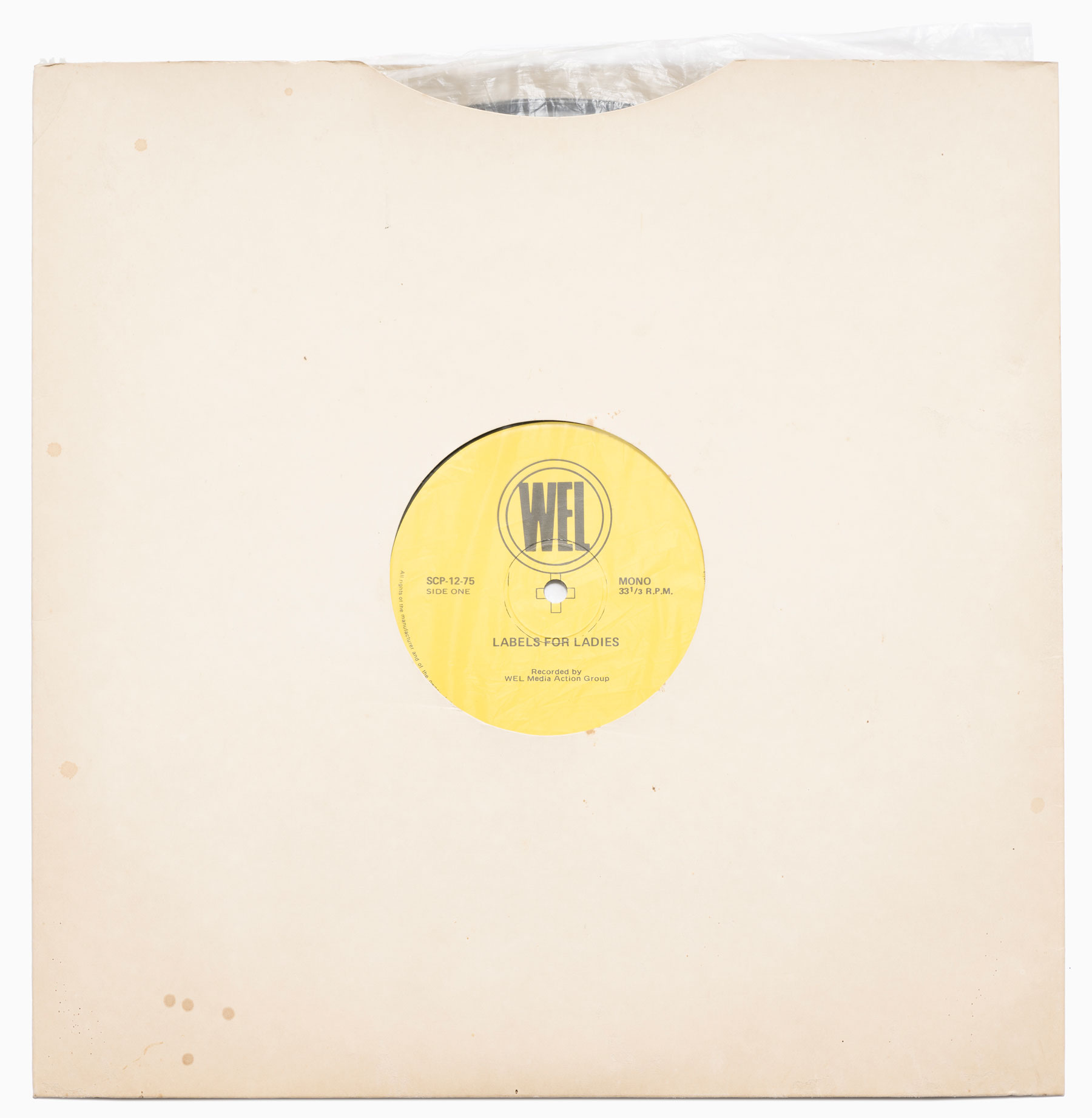 A cream cover over a vinyl record. The yellow record label shows through a hole in the cover's centre. Label text reads 'WEL: labels for ladies'.