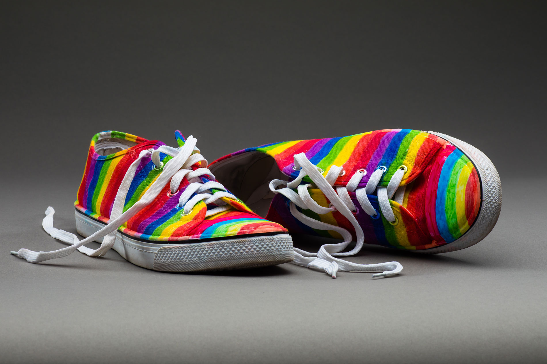 A pair of sneakers painted with rainbow stripes.