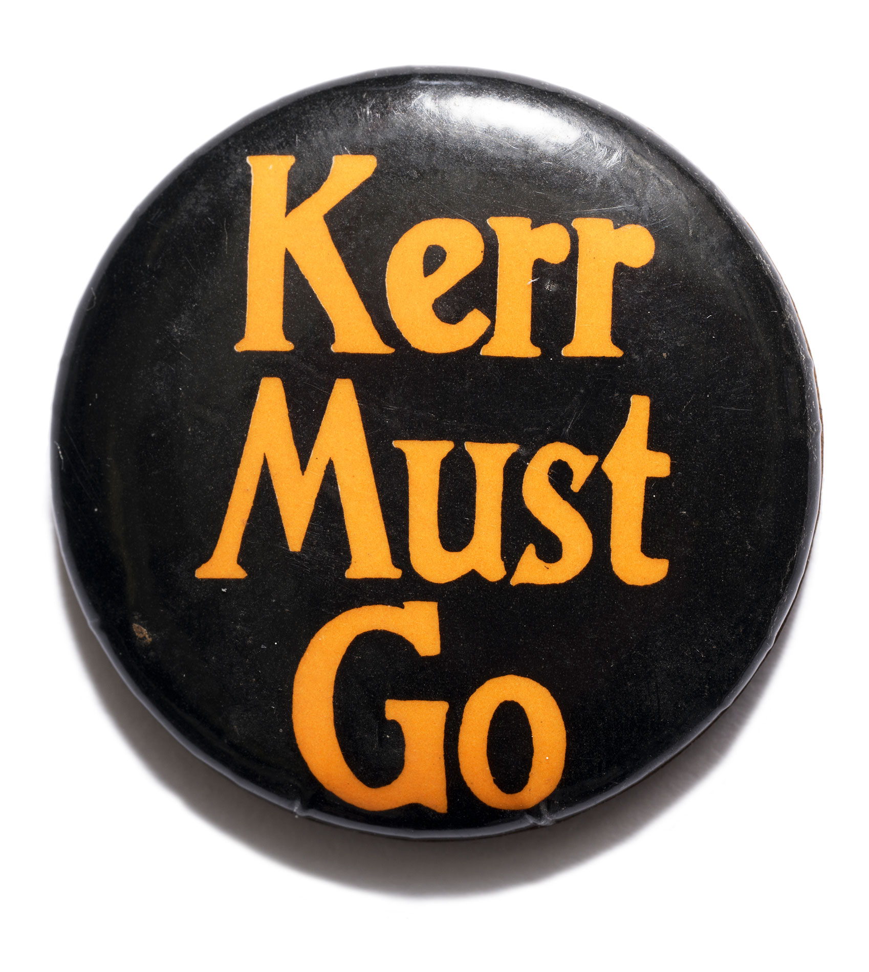A black badge with orange text which says 'Kerr must go'.