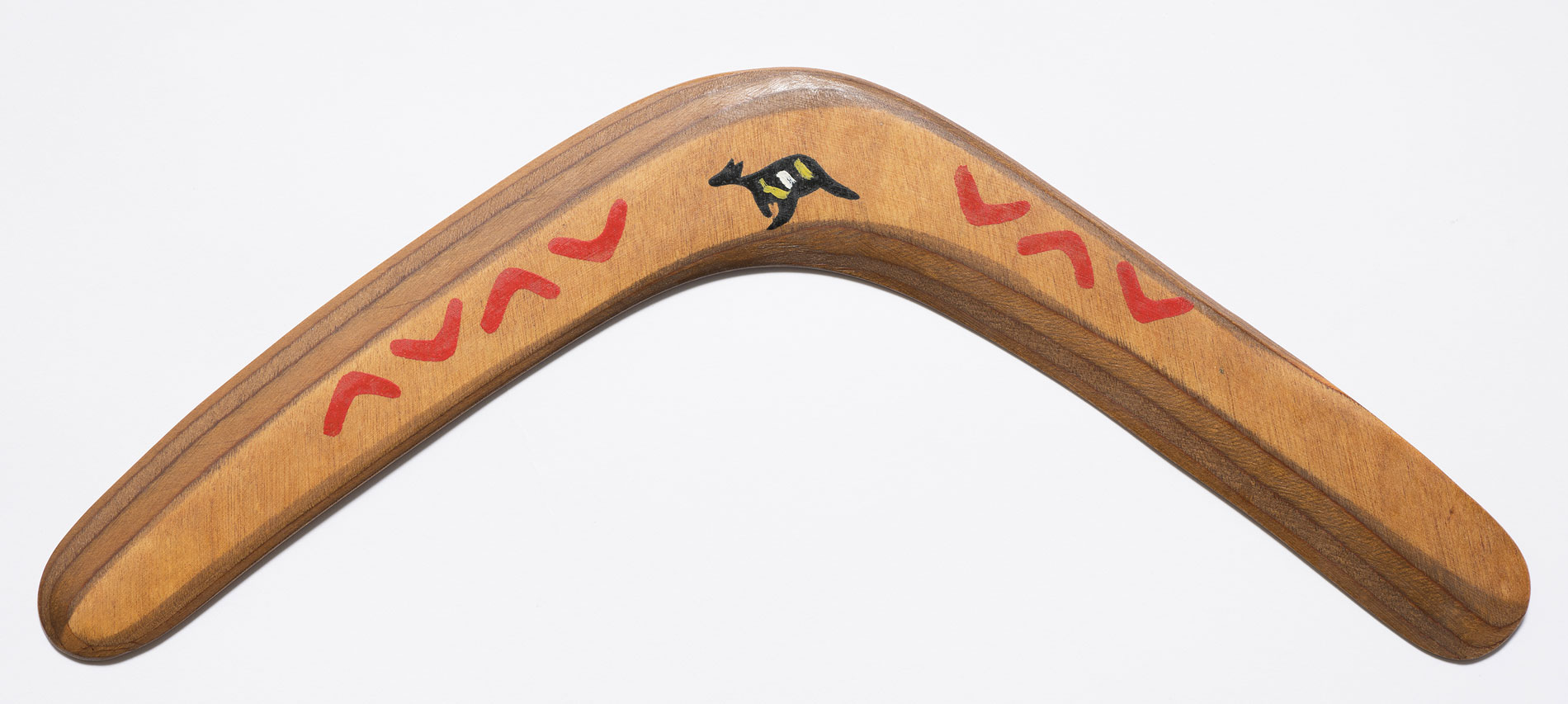 A wooden boomerang featuring a design of small boomerangs and a kangaroo.