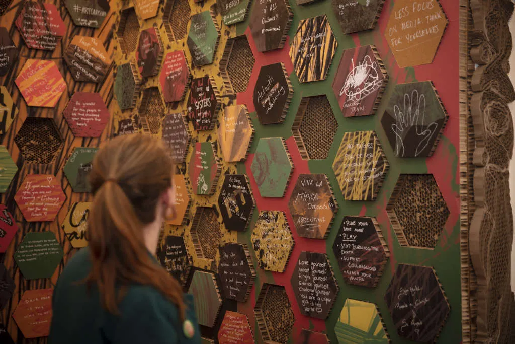 A visitor looking at a wall of honeycomb-styled blocks in the exhibition. A visitor looking at a wall of honeycomb-styled blocks in the exhibition.