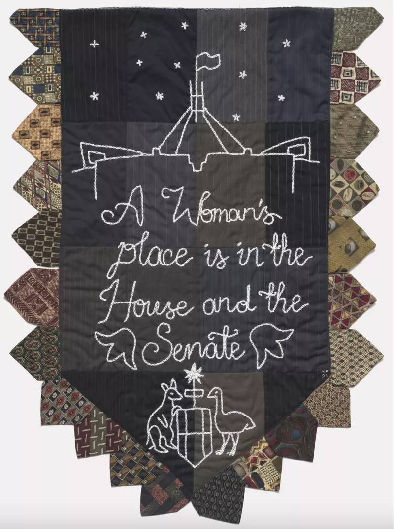 Black, grey and brown embroidered banner with the Australian coat of arms that says 'A woman's place is in the House and the Senate'. Black, grey and brown embroidered banner with the Australian coat of arms that says 'A woman's place is in the House and the Senate'.