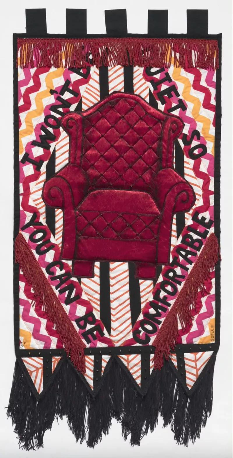 Red, black and white embroidered banner with a red wing chair in the middle of it, surrounded by the message 'I won't be quiet so you can be comfortable'. Red, black and white embroidered banner with a red wing chair in the middle of it, surrounded by the message 'I won't be quiet so you can be comfortable'.