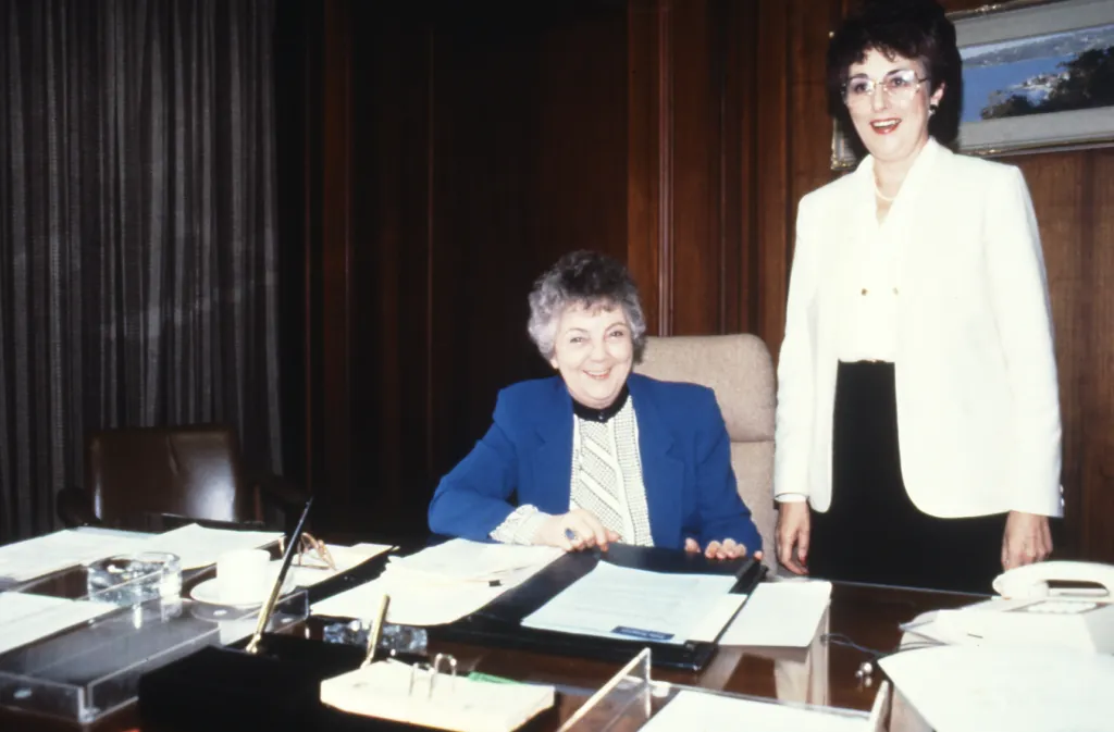 Speaker Joan Child and Marie Donnelly standing behind her desk. 1988, film photo. Speaker Joan Child and Marie Donnelly standing behind her desk. 1988, film photo.