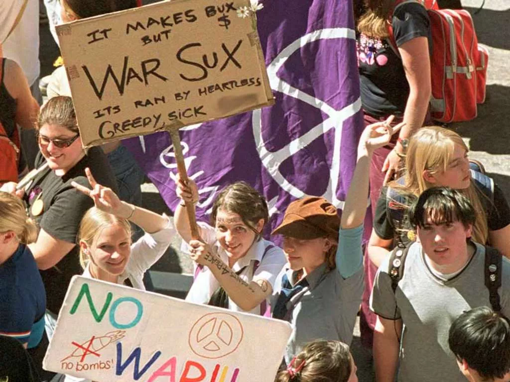 A group of school children wave anti-war flags and signs. A group of school children wave anti-war flags and signs.