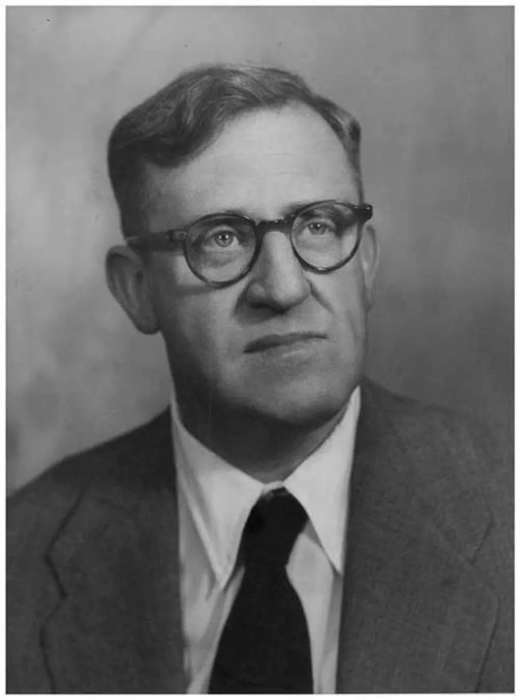 A black and white portrait photograph of Arthur Calwell, a man wearing dark-framed glasses, suit jacket and a black tie. A black and white portrait photograph of Arthur Calwell, a man wearing dark-framed glasses, suit jacket and a black tie.