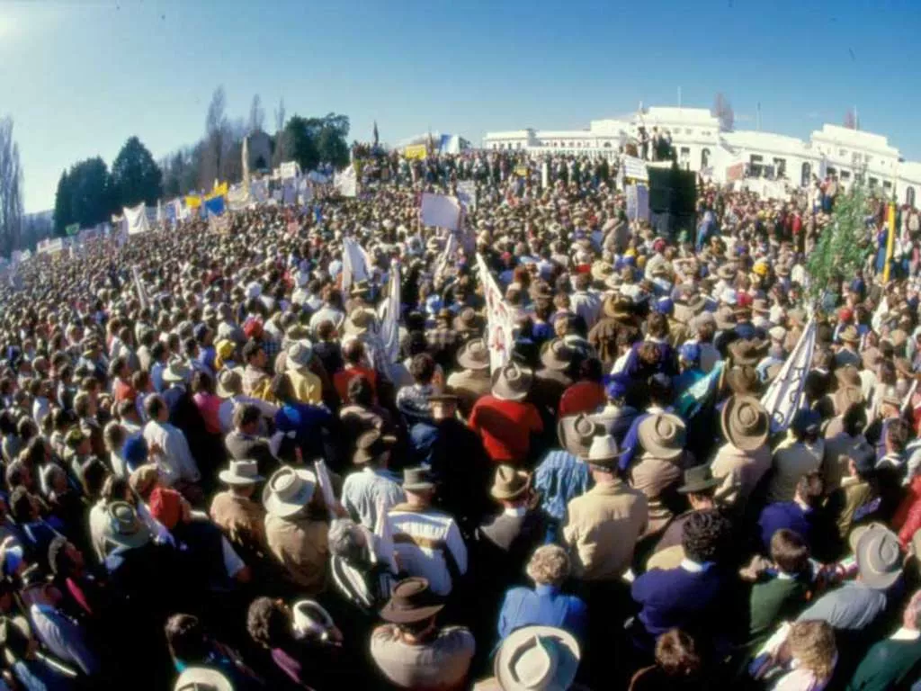 A very large crowd of farmers, many wearing hats and waving banners, rallying in front of Old Parliament House. A very large crowd of farmers, many wearing hats and waving banners, rallying in front of Old Parliament House.