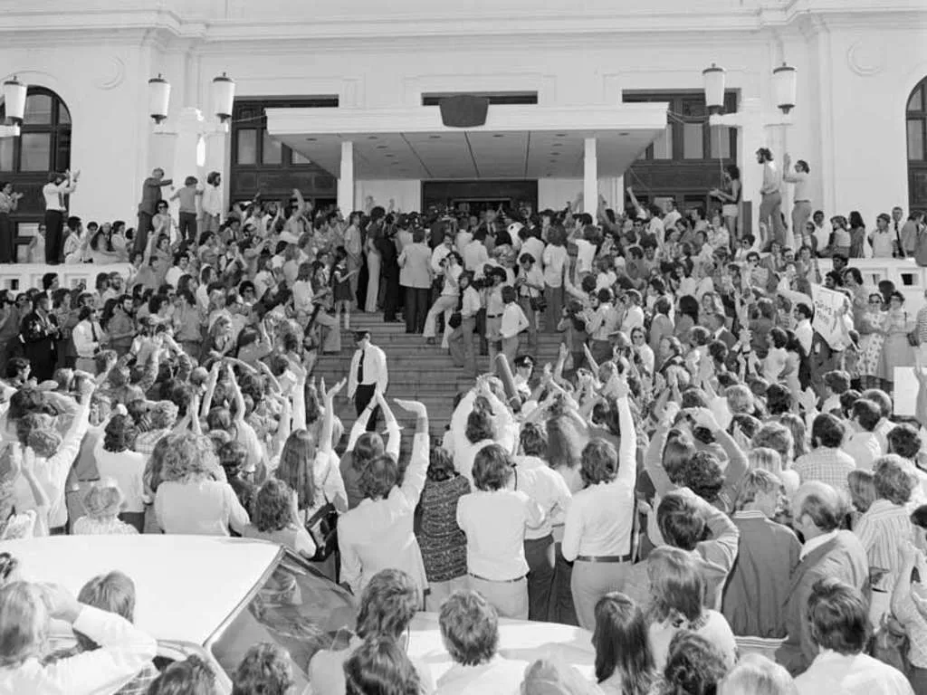 A crowd of people standing at the steps of Old Parliament House as Gough Whitlam steps out to address them. A crowd of people standing at the steps of Old Parliament House as Gough Whitlam steps out to address them.