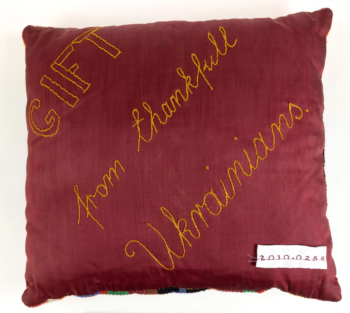 A velvet cushion with hand embroidered text that says gift from thankful Ukrainians. A velvet cushion with hand embroidered text that says gift from thankful Ukrainians.