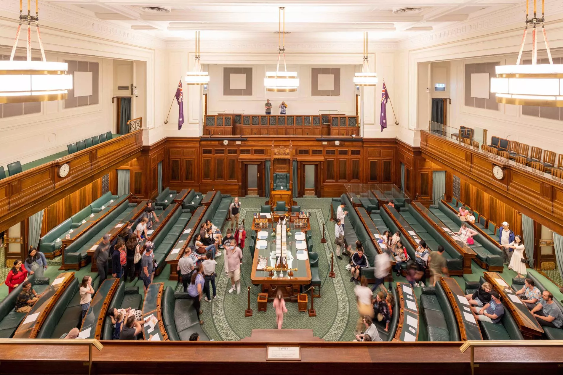 A view looking down onto the House of Representatives Chamber which has green carpet and green leather and timber benches in a U-shape surrounding a central table. A view looking down onto the House of Representatives Chamber which has green carpet and green leather and timber benches in a U-shape surrounding a central table.