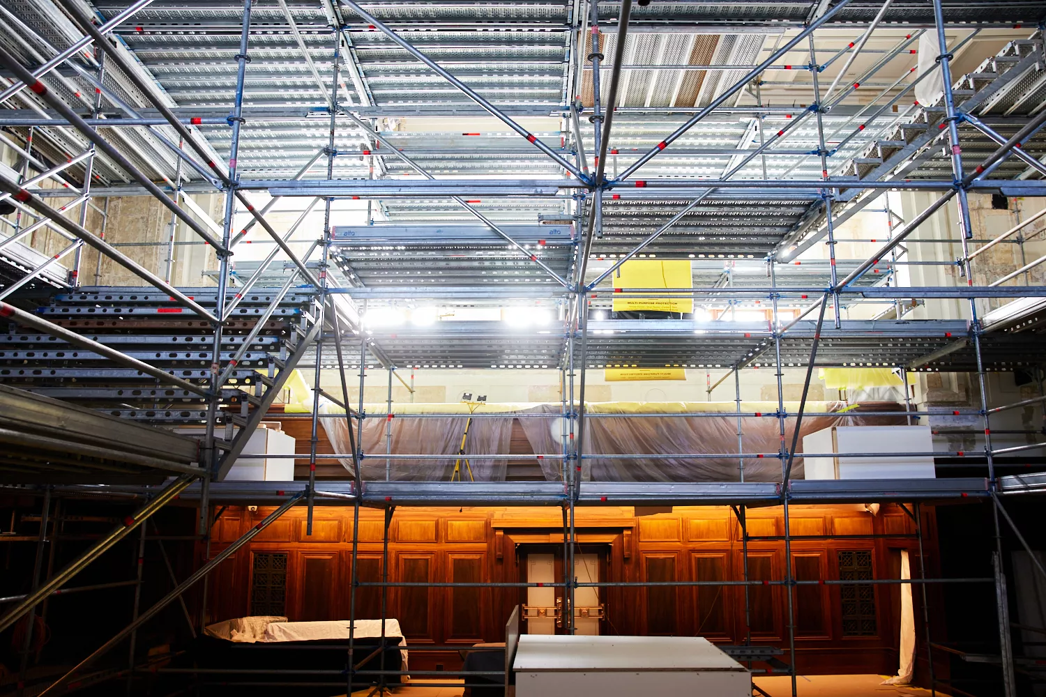 A large, tall metal scaffolding rises from the floor to the ceiling in the centre of the House of Representatives chamber. Wooden panels and a set of doors are visible at the bottom of the scaffolding. A large, tall metal scaffolding rises from the floor to the ceiling in the centre of the House of Representatives chamber. Wooden panels and a set of doors are visible at the bottom of the scaffolding.