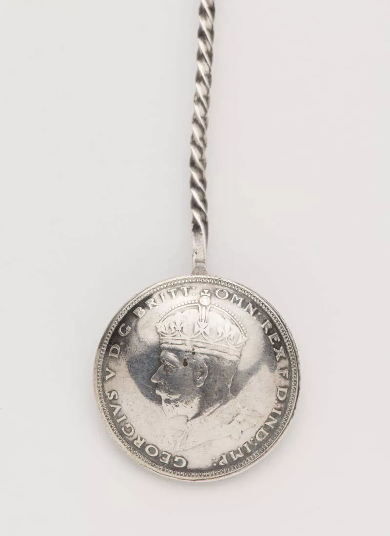 Photograph of the back of a souvenir spoon depicting an impressed side portrait of King George. Photograph of the back of a souvenir spoon depicting an impressed side portrait of King George.