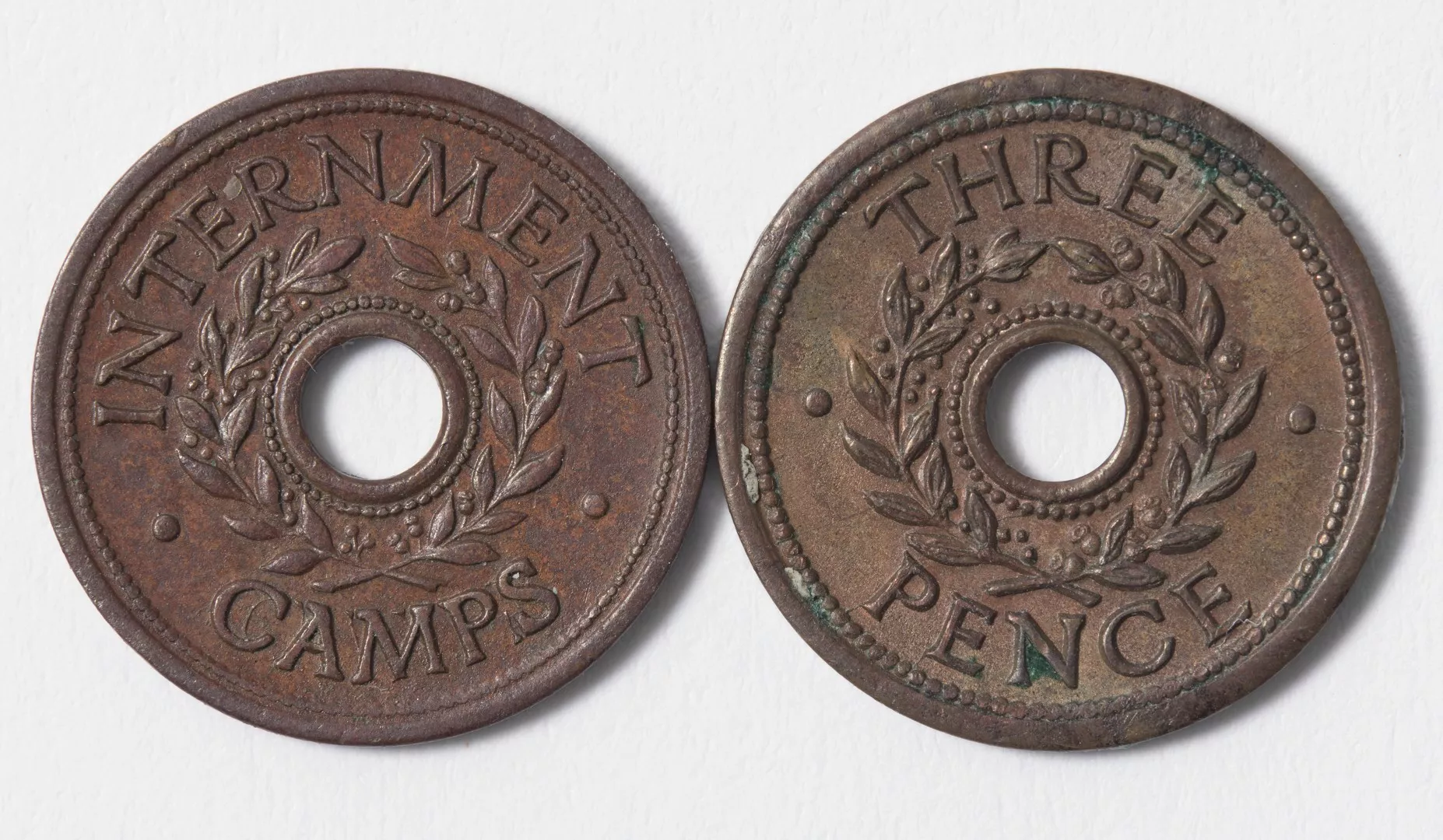The front and back of a threepenny copper internment camp token with the words 'internment camps' and 'three pence' and featuring a wreath of eucalyptus and an olive branch.jpg The front and back of a threepenny copper internment camp token with the words 'internment camps' and 'three pence' and featuring a wreath of eucalyptus and an olive branch.jpg