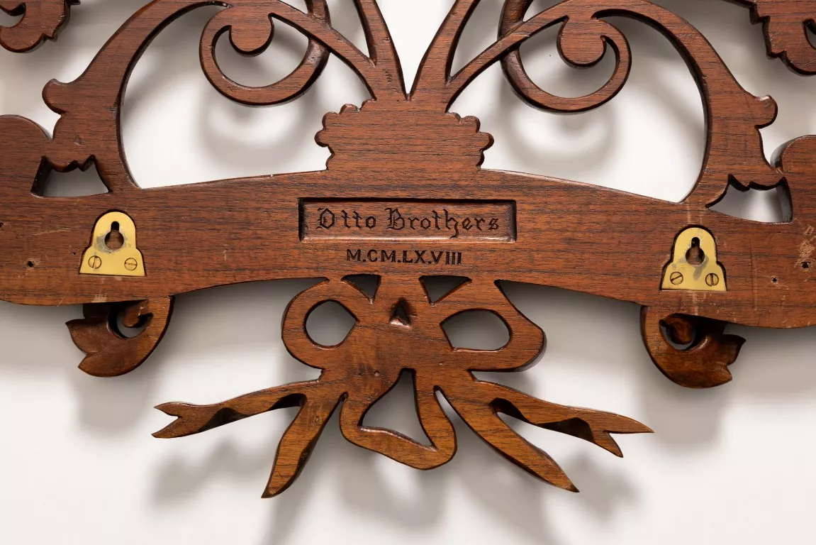 A detail close up of an ornate wooden coat of arms with 'Otto Brothers' carved into the wood. A detail close up of an ornate wooden coat of arms with 'Otto Brothers' carved into the wood.