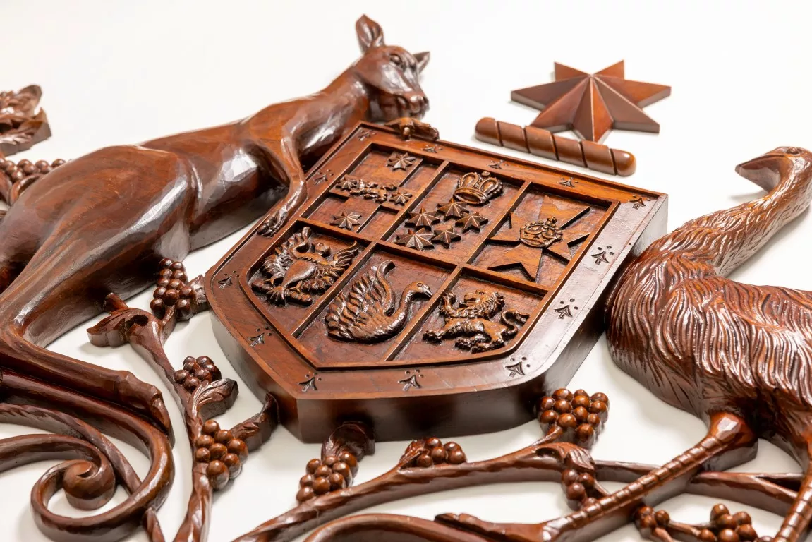 A close up of a wooden coat of arms with a kangaroo and an emu on either side of a shield. A close up of a wooden coat of arms with a kangaroo and an emu on either side of a shield.