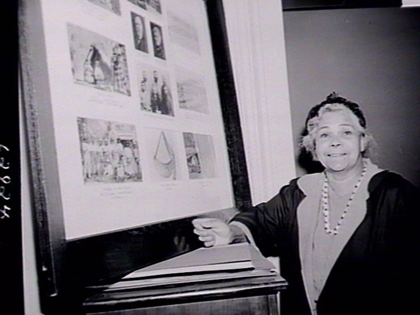 A woman, Margaret Tucker, stands next to a large picture frame filled with images. A woman, Margaret Tucker, stands next to a large picture frame filled with images.