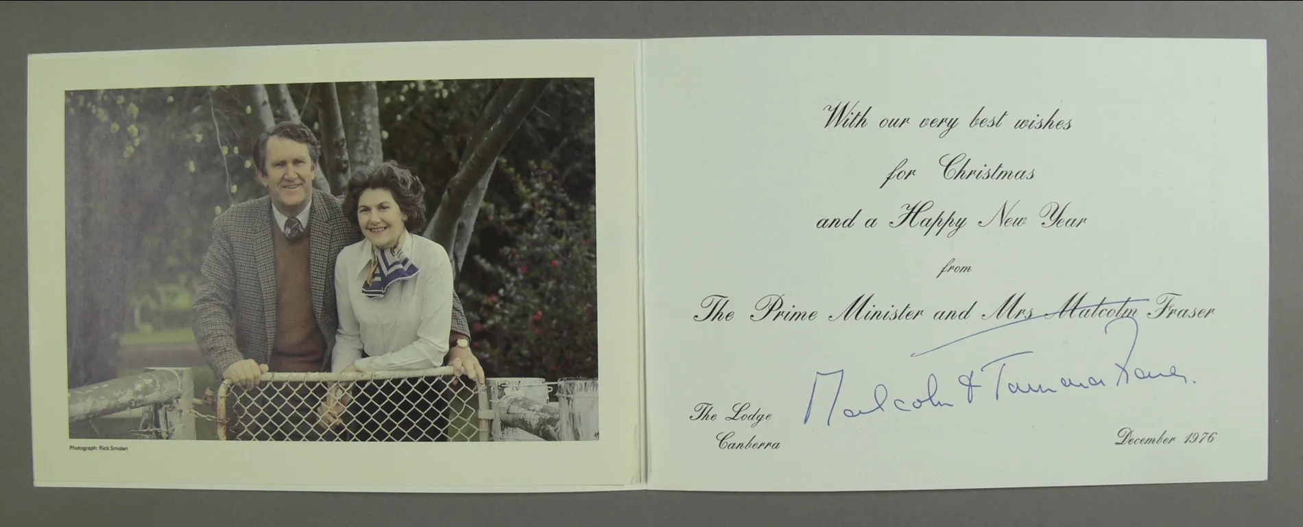 A christmas card featuring a photo of Malcolm Fraser wearing a tweed jacket and Tamie Fraser wearing a white blouse and blue striped scarf, posing together in from of a gate. A christmas card featuring a photo of Malcolm Fraser wearing a tweed jacket and Tamie Fraser wearing a white blouse and blue striped scarf, posing together in from of a gate.