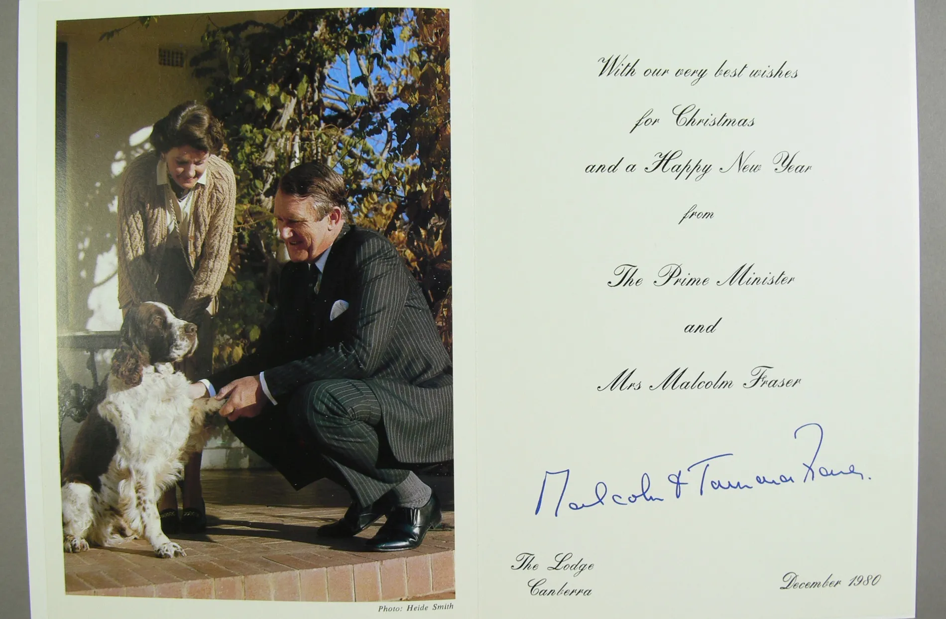 A Christmas card featuring a photo of Malcolm and Tamie Fraser with their dog, Droopy, a brown and white English springer spaniel. A Christmas card featuring a photo of Malcolm and Tamie Fraser with their dog, Droopy, a brown and white English springer spaniel.