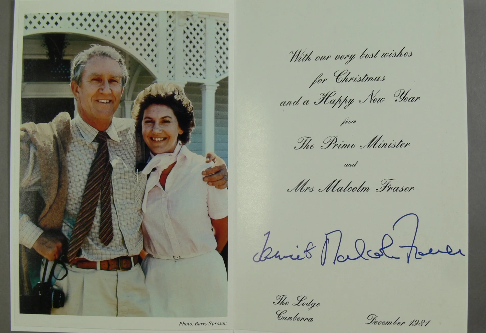 A Christmas card featuring an image of Malcolm Fraser standing with a tweed jacket hanging on his shoulder, and an arm around Tamie Fraser. wearing a pink blouse and white neckscarf. A Christmas card featuring an image of Malcolm Fraser standing with a tweed jacket hanging on his shoulder, and an arm around Tamie Fraser. wearing a pink blouse and white neckscarf.