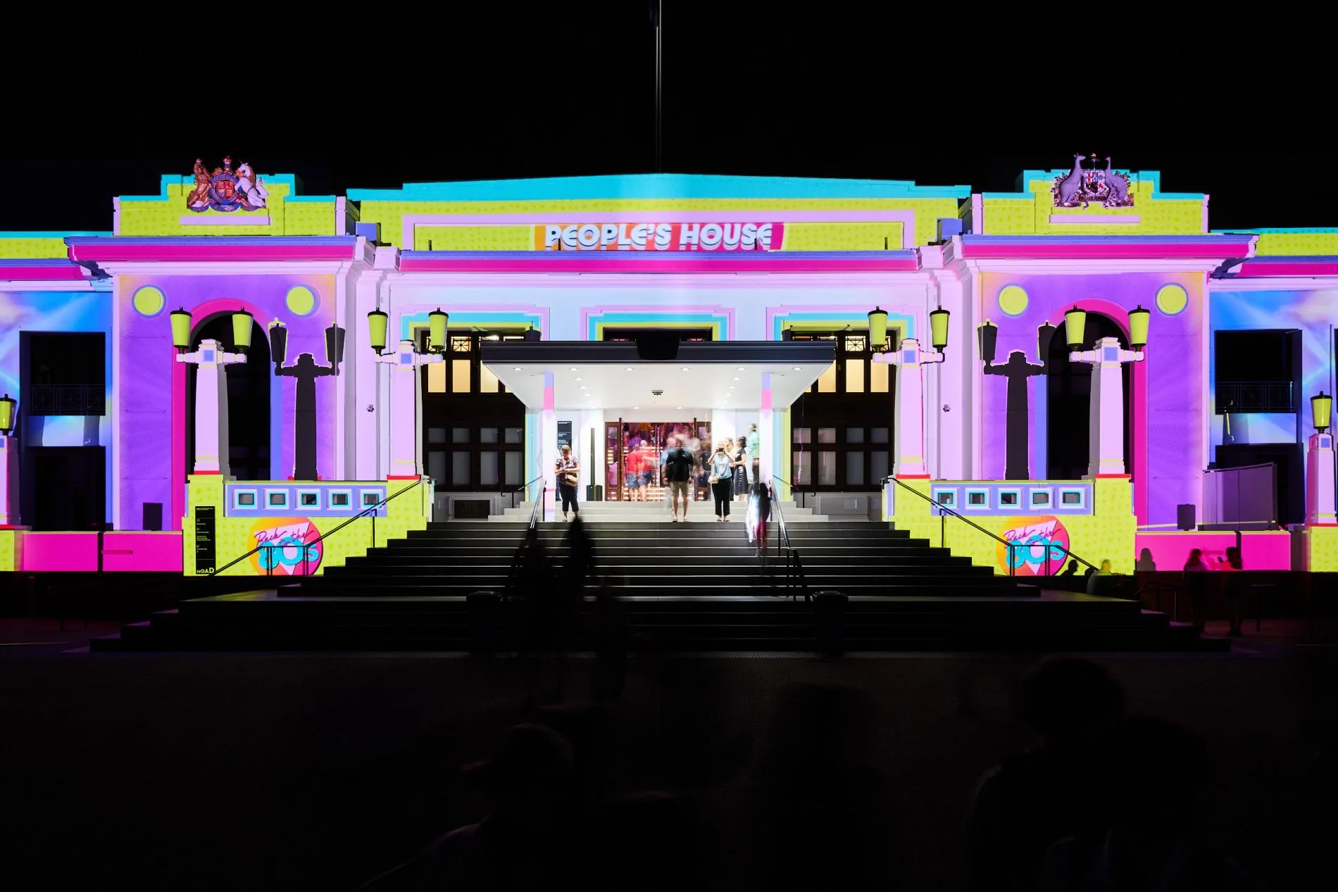 The front of Old Parliament House lit up in bright neon colours for Enlighten 2024.