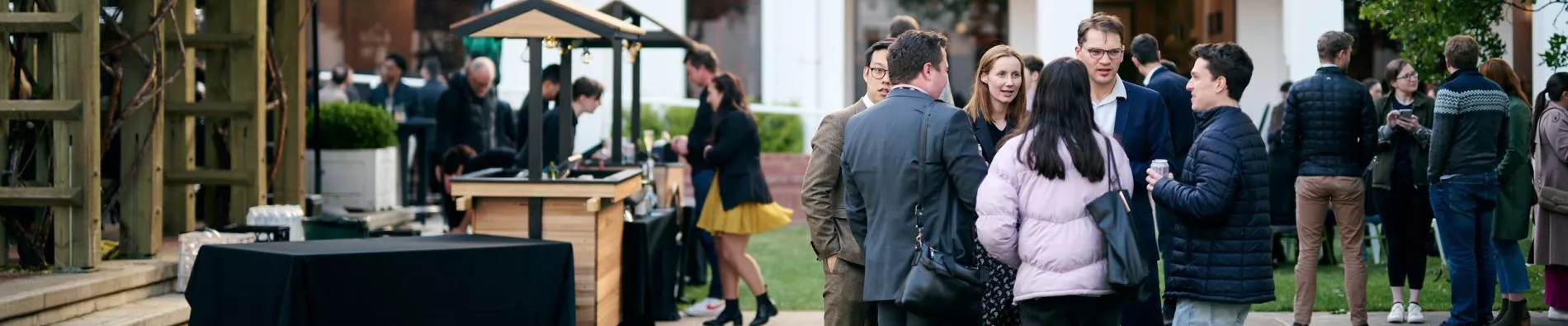 Groups of people socialising on the lawn in the House of Representatives courtyard.