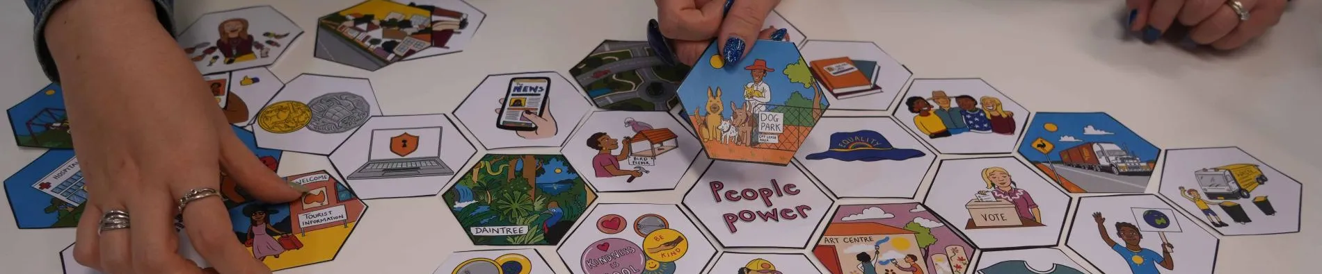 Hands move hexagon-shaped tiles featuring words and illustrations. 