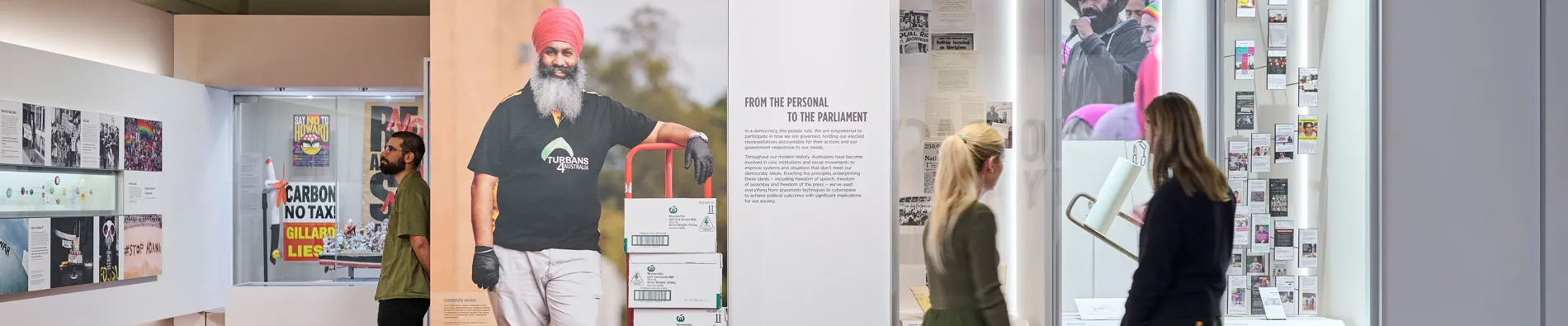 Three people read panels in the Democracy Are You In exhibit in Old Parliament House.