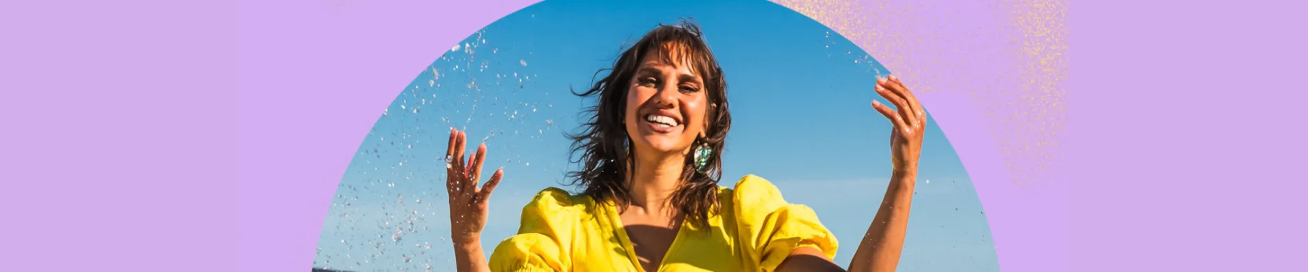 An image of Kirli Saunders playing in the water at a beach in front of an abstract background with block colours.