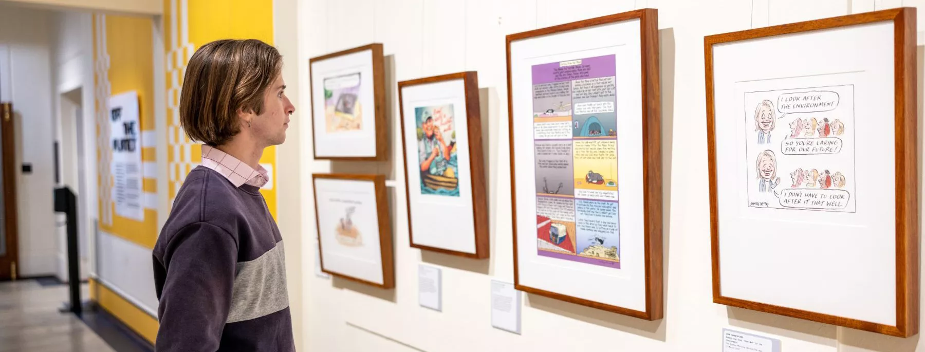 A visitor looking at the framed cartoons lining the walls