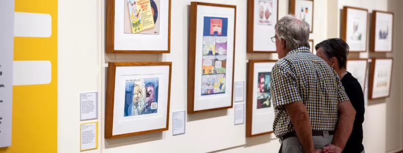Visitors looking at the framed cartoons on the walls