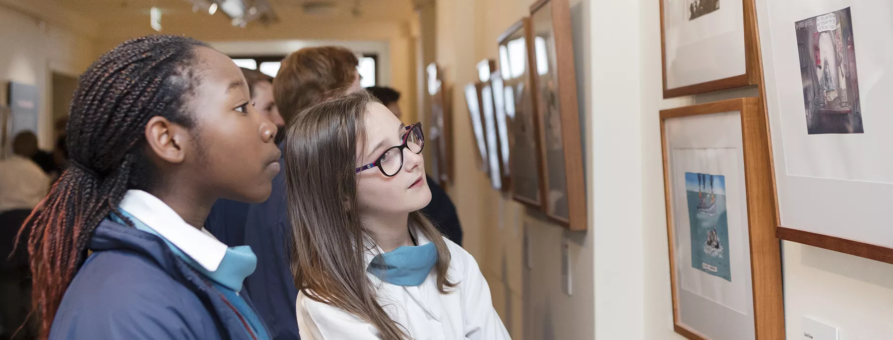 Two school children looking at the artwork in Behind the Lines
