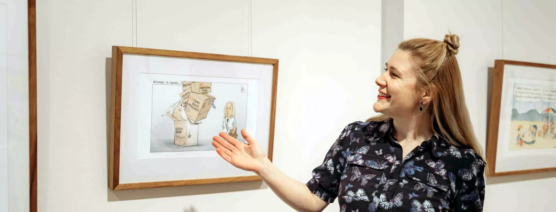 A MoAD educator stands in front of a political cartoon hanging on the wall. 