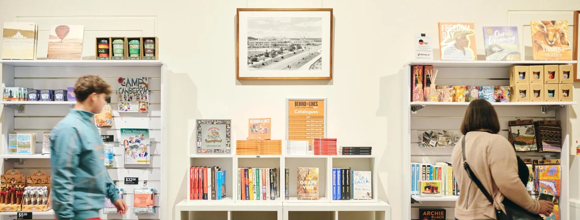 Two people browse books and other shop products on shelves. 