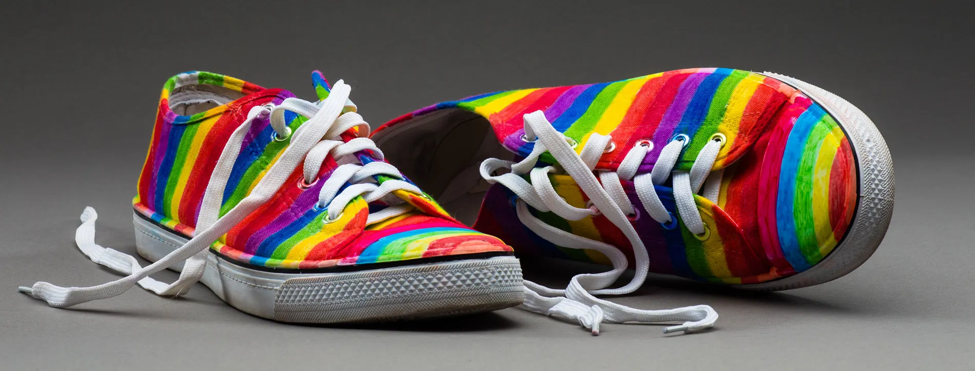 A pair of sneakers painted with rainbow stripes.
