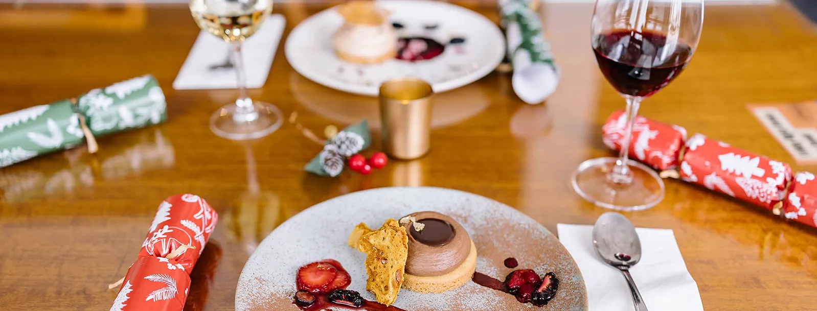 Dessert, wine glasses and Christmas crackers on a restaurant table. 
