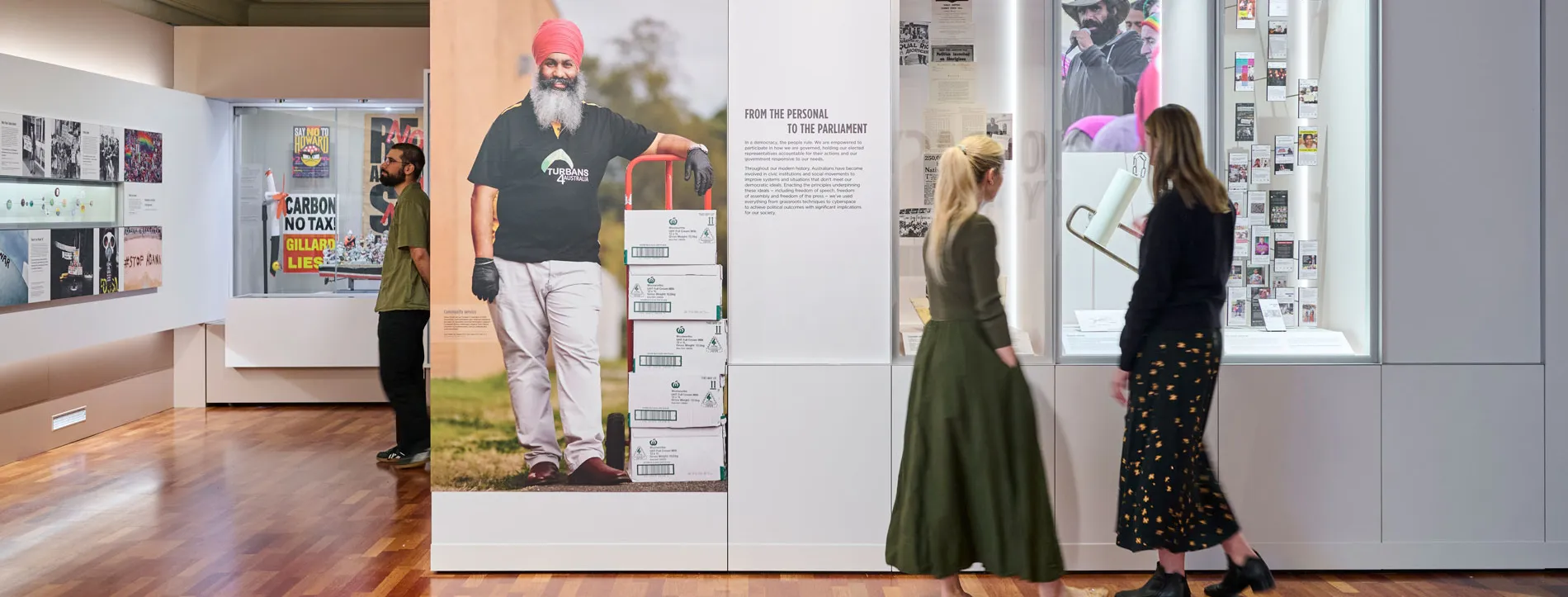 Three people read panels in the Democracy Are You In exhibit in Old Parliament House.