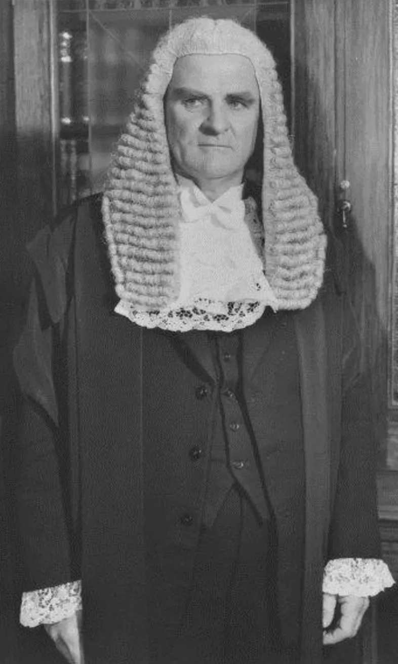 Speaker of the House, Archie Cameron, wearing a black ceremonial attire and wig. Speaker of the House, Archie Cameron, wearing a black ceremonial attire and wig.