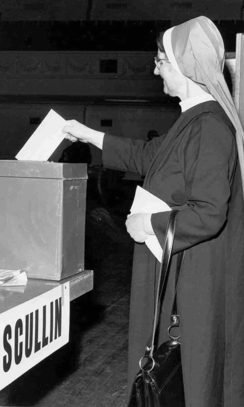 A nun wearing a habit puts a ballot paper into a ballot box marked 'Scullin'. A nun wearing a habit puts a ballot paper into a ballot box marked 'Scullin'.