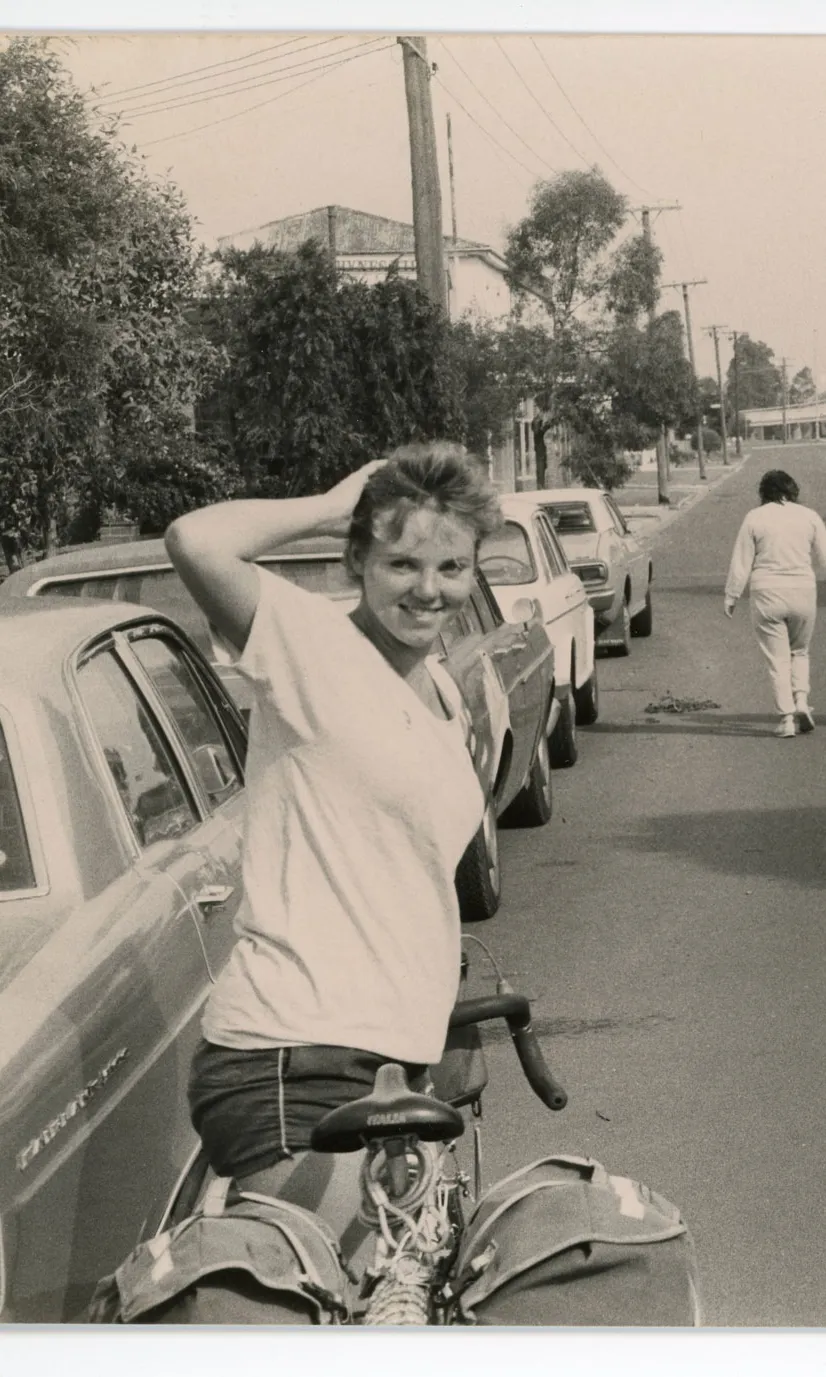 Two women stand with their bicycles beside a car on a suburban street. Two women stand with their bicycles beside a car on a suburban street.