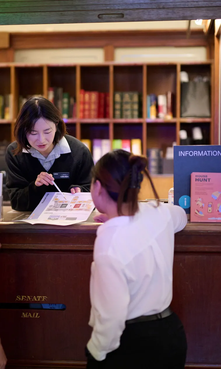 A museum staff member shows a map to visitors in King's Hall at Old Parliament House.