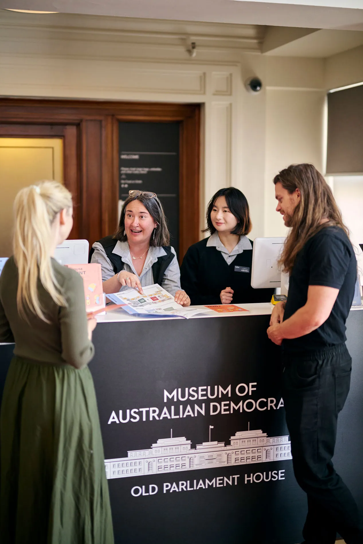 Museum staff show a brochure to visitors at the reception desk at Old Parliament House.